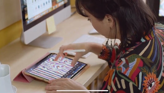 Woman using a digital tablet to create AI art in fashion design with colorful patterns on screen