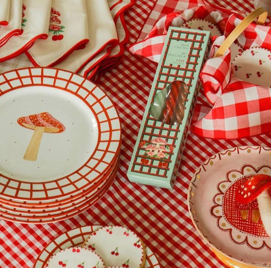 Vichy Garden Collection candle review showcasing mushroom and cherry-themed plates and decorative kitchen linens on a red checkered tablecloth