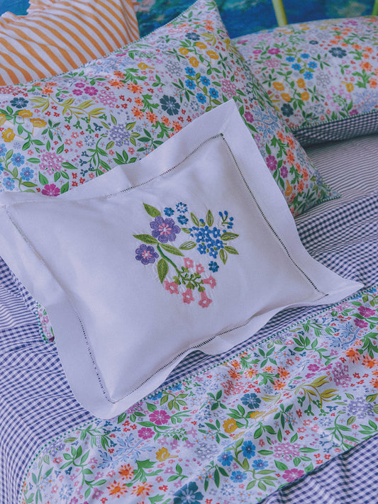 Floral bedding summer collection featuring colorful floral prints and embroidered pillow on a cozy bed