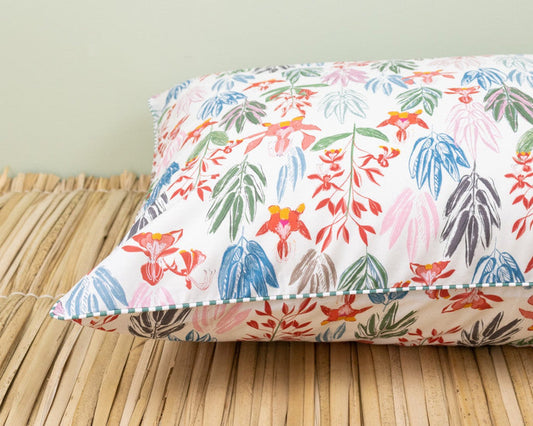 Decorative pillow with colorful tropical floral print inspired by Burle Marx inspired home decor on a woven mat