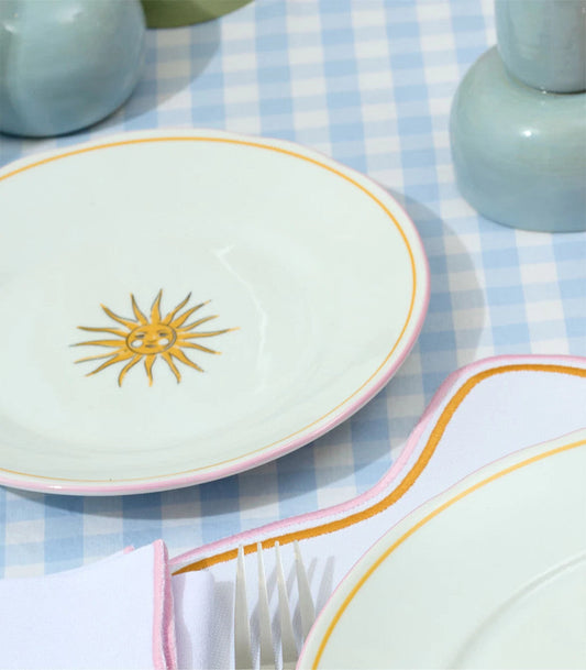 White plate with gold sun design on a blue checkered tablecloth featuring items from Cian Candle’s Wishes Collection